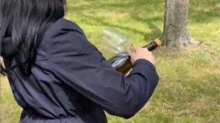 Woman uses glass to open bottle of champagne