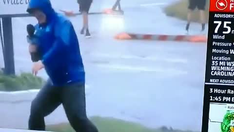 Weather Channel reporter braces against wind as others just stroll by