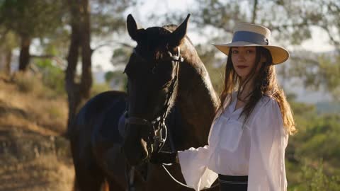 Portrait of confident slim beautiful woman looking at camera holding horse