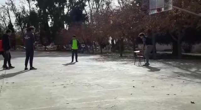 Guys jumping off chair to rebound basketball off of backboard second guy falls and chair falls over